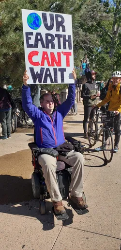 Chris Hinds holding 'The Earth Can’t Wait' sign